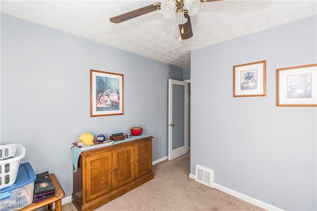 interior space featuring visible vents, baseboards, light colored carpet, a textured ceiling, and a ceiling fan