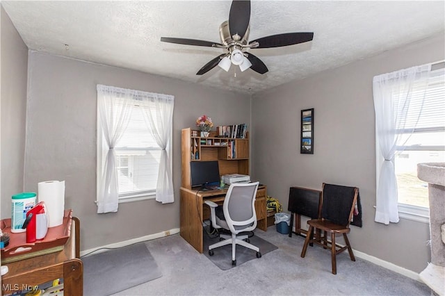 carpeted office featuring a wealth of natural light, baseboards, a textured ceiling, and ceiling fan