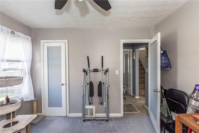 exercise area with visible vents, carpet floors, a textured ceiling, and ceiling fan