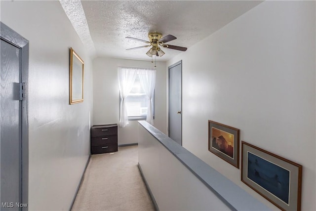 hallway with light carpet and a textured ceiling