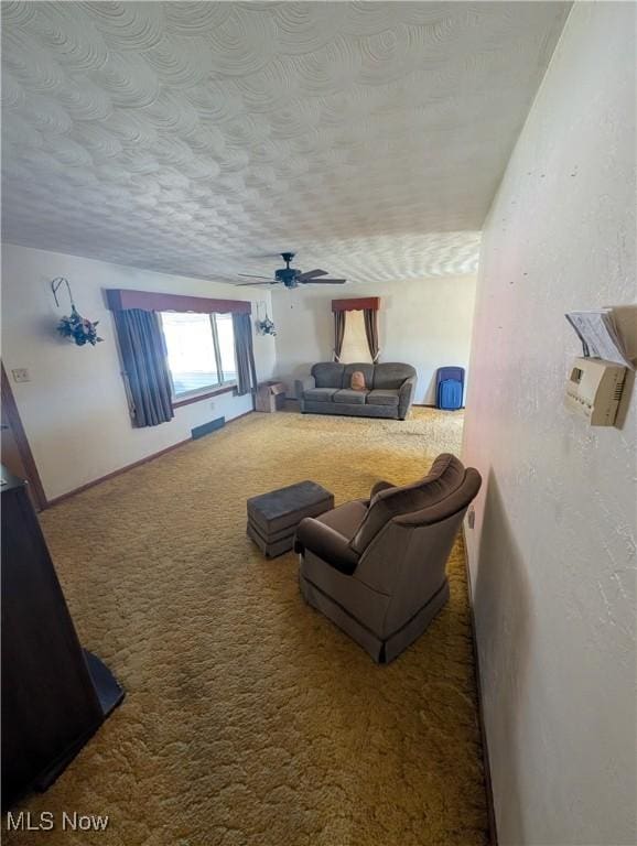 carpeted living room featuring a ceiling fan and a textured ceiling