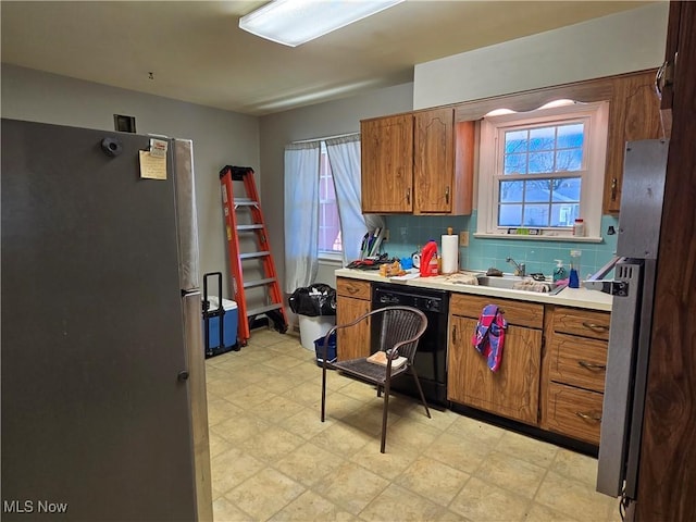 kitchen featuring dishwasher, light floors, brown cabinets, and freestanding refrigerator