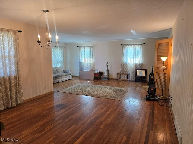 living room featuring baseboards, an inviting chandelier, and hardwood / wood-style floors