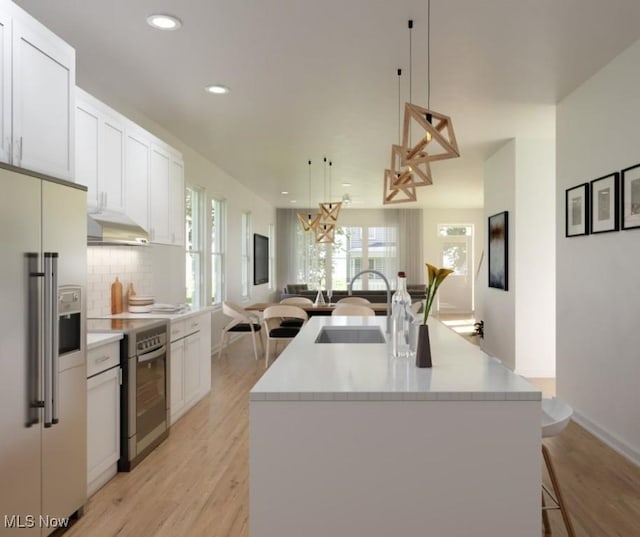 kitchen with a kitchen island with sink, decorative backsplash, appliances with stainless steel finishes, open floor plan, and a chandelier