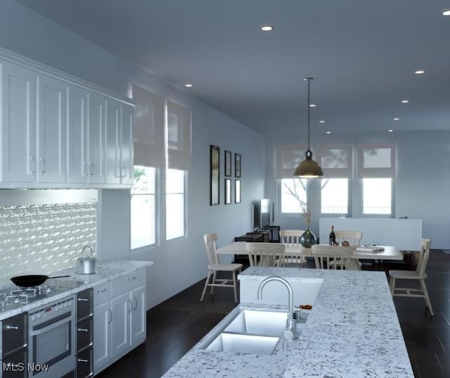 kitchen featuring wall oven, white cabinetry, a wealth of natural light, and a sink