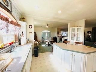 kitchen featuring a kitchen island, light countertops, white cabinets, light colored carpet, and open floor plan