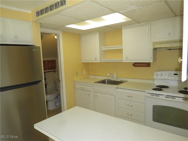 kitchen with electric range, visible vents, a sink, under cabinet range hood, and freestanding refrigerator