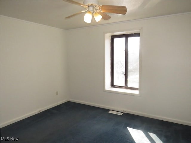 spare room with visible vents, a ceiling fan, baseboards, and ornamental molding