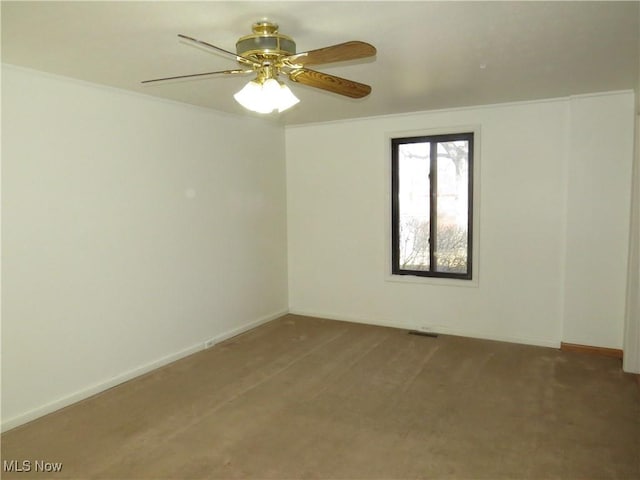 carpeted empty room featuring baseboards, ceiling fan, and crown molding