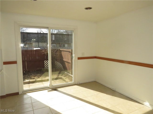 tiled spare room featuring baseboards