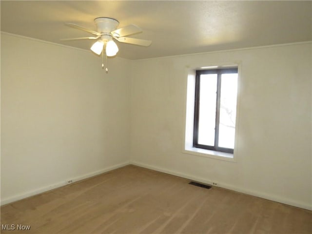 spare room featuring a ceiling fan, visible vents, and baseboards