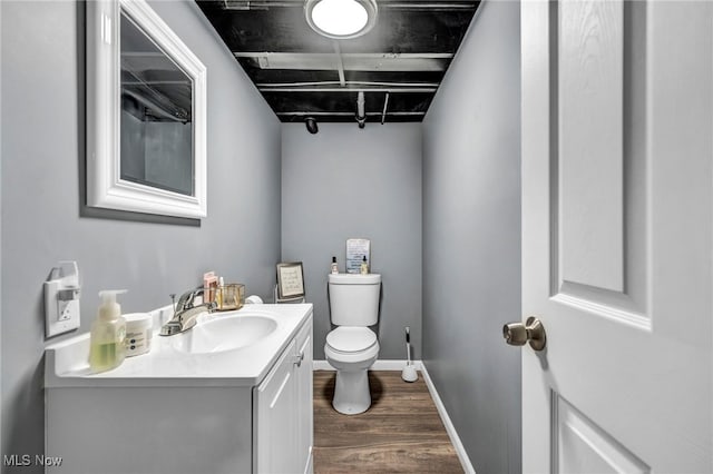 bathroom with baseboards, toilet, wood finished floors, and vanity