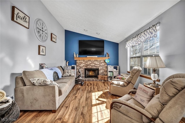 living room featuring lofted ceiling, a textured ceiling, wood finished floors, and a fireplace