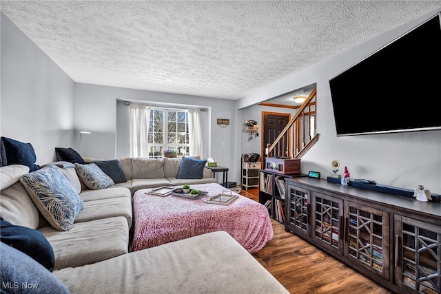 living room featuring stairway, a textured ceiling, and wood finished floors