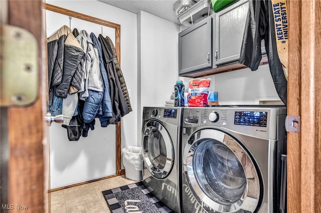 laundry area with a textured ceiling, cabinet space, and washer and clothes dryer