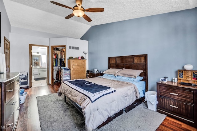 bedroom featuring visible vents, a textured ceiling, dark wood finished floors, a closet, and vaulted ceiling