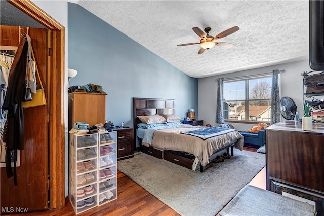 bedroom featuring lofted ceiling, a textured ceiling, wood finished floors, and a ceiling fan