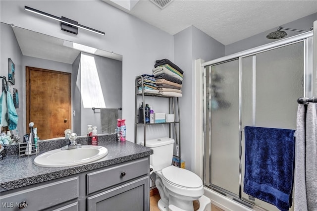 bathroom with visible vents, a shower stall, a textured ceiling, and vanity