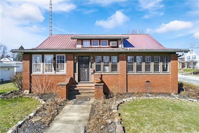 bungalow-style house featuring metal roof, brick siding, and a standing seam roof