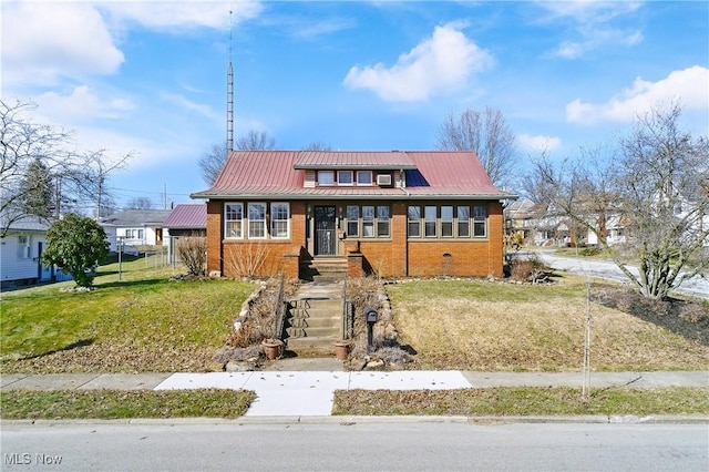 bungalow-style home featuring metal roof, brick siding, a front lawn, and a standing seam roof