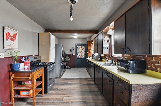 kitchen with beam ceiling, light wood-style flooring, a sink, stainless steel appliances, and light countertops