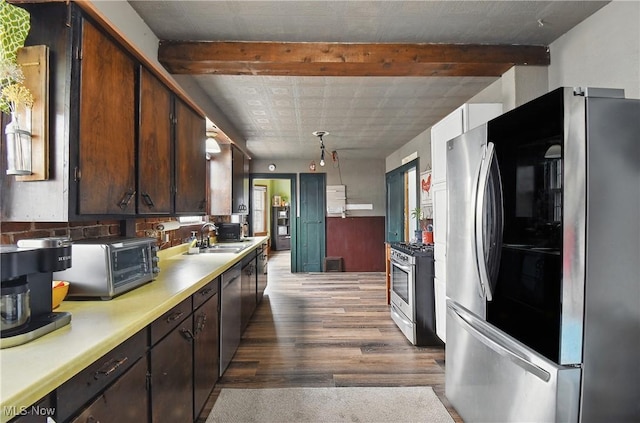 kitchen featuring a sink, appliances with stainless steel finishes, light countertops, dark brown cabinets, and dark wood-style flooring