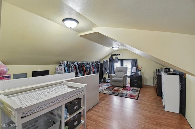 additional living space featuring a textured ceiling, vaulted ceiling, and light wood finished floors