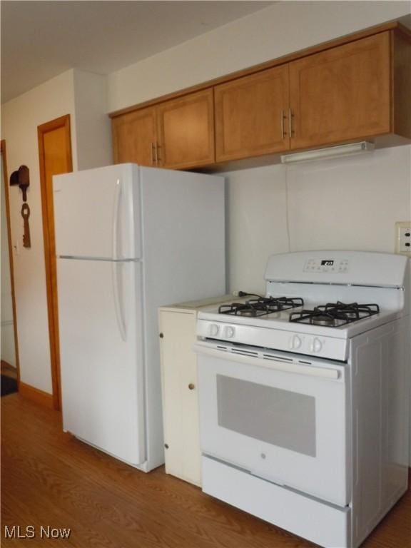 kitchen with white appliances, brown cabinets, and wood finished floors