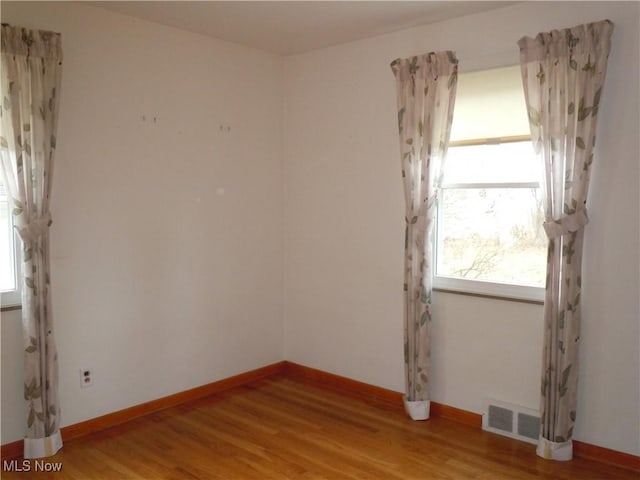 unfurnished room featuring baseboards, visible vents, and light wood finished floors