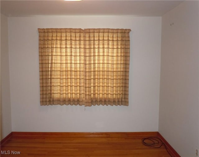 unfurnished room featuring wood finished floors and baseboards