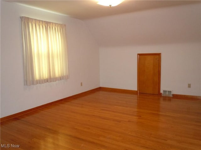 additional living space featuring lofted ceiling, baseboards, visible vents, and light wood finished floors