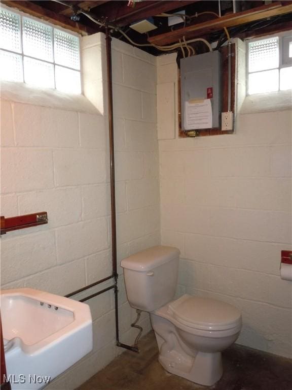 bathroom featuring electric panel, toilet, and concrete flooring