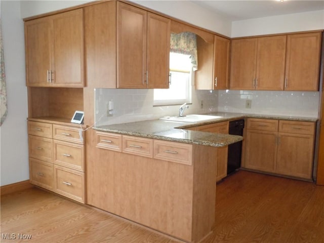 kitchen with dishwasher, decorative backsplash, light wood-type flooring, and a sink