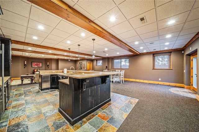 kitchen featuring baseboards, visible vents, a large island with sink, a sink, and open floor plan