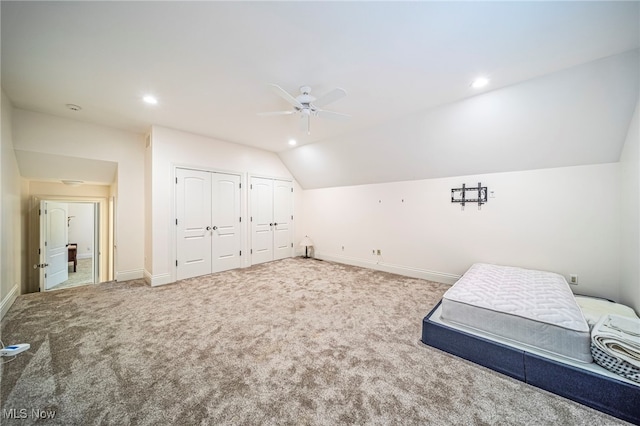 bedroom featuring baseboards, lofted ceiling, recessed lighting, carpet flooring, and two closets