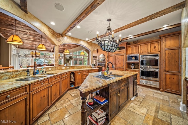 kitchen with a warming drawer, a notable chandelier, stone tile floors, and appliances with stainless steel finishes