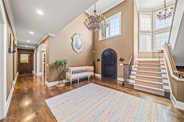 foyer entrance with stairway, arched walkways, a notable chandelier, and wood finished floors