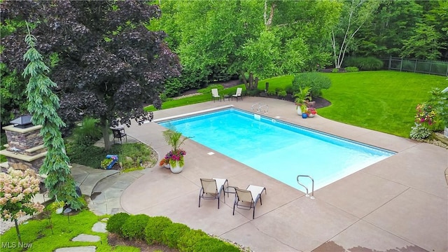 outdoor pool with a patio area, a yard, and fence