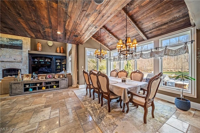 dining room with a notable chandelier, lofted ceiling with beams, stone tile floors, wooden ceiling, and baseboards