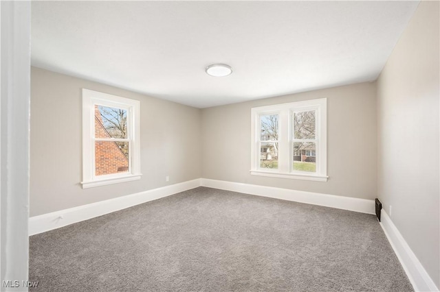 carpeted spare room featuring a wealth of natural light and baseboards