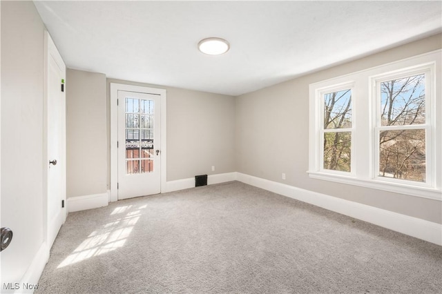 carpeted spare room with visible vents and baseboards