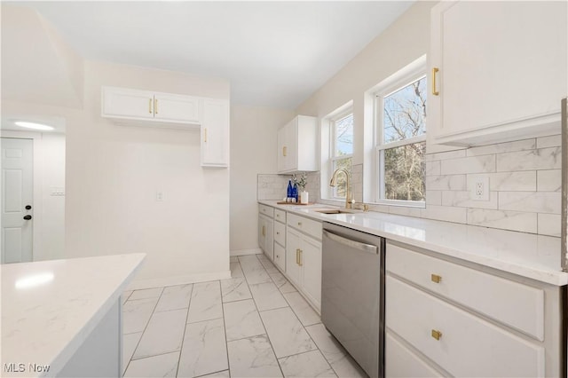 kitchen with a sink, decorative backsplash, white cabinets, stainless steel dishwasher, and marble finish floor