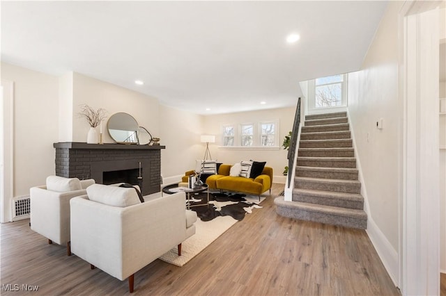 living area with visible vents, wood finished floors, a fireplace, baseboards, and stairs