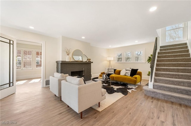 living room with stairs, recessed lighting, light wood-type flooring, and a fireplace