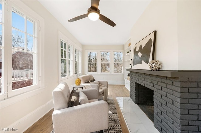 sunroom with a brick fireplace and ceiling fan