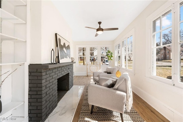 sunroom featuring a fireplace and ceiling fan