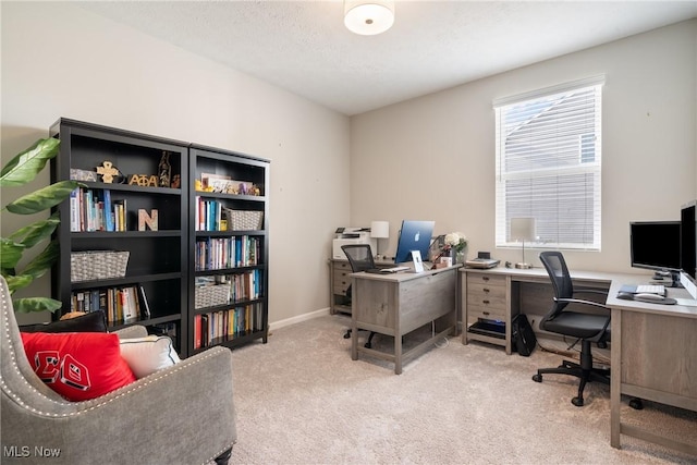 carpeted home office with a textured ceiling and baseboards