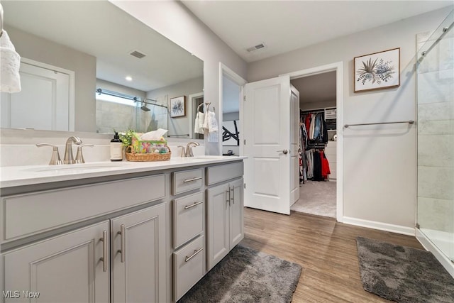 bathroom featuring a shower stall, double vanity, visible vents, and a sink