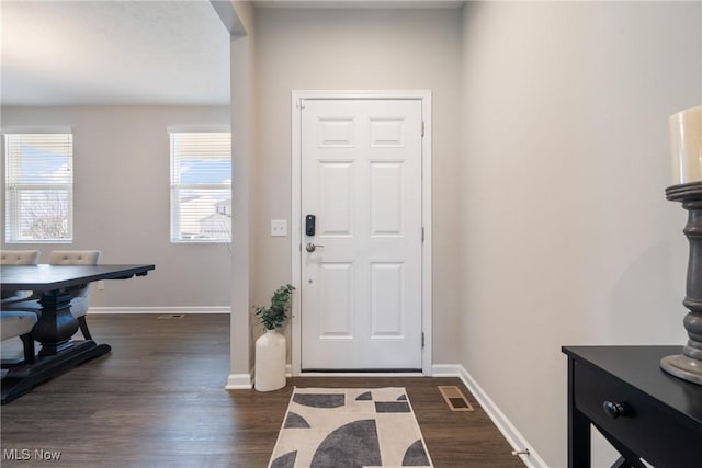 foyer entrance featuring baseboards, visible vents, and dark wood-style flooring