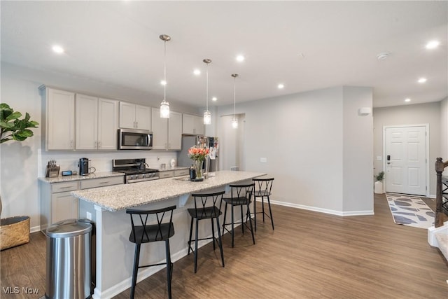 kitchen featuring a center island with sink, appliances with stainless steel finishes, wood finished floors, and recessed lighting